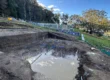 Flooded footings on a Lou Projects building site after rain, with water pooled across the excavated slab