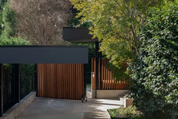 Rolling timber slat front gate and cantilevered entry awning at Pymble home by Lou Projects
