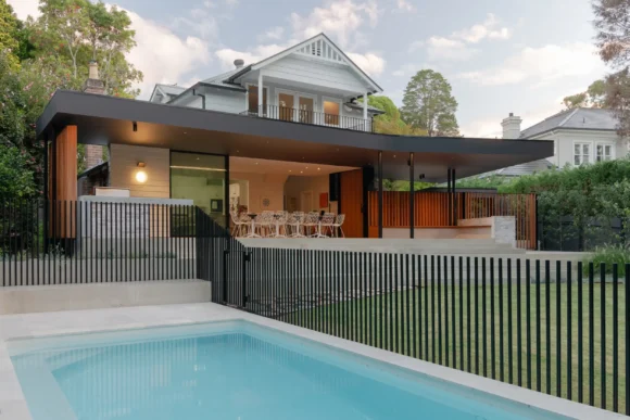 Twilight view of Pymble home renovation with illuminated interior, pool and modern rear extension by Lou Projects