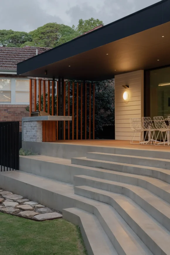 Cantilevered steel awning, timber slat screening and concrete steps at dusk – Pymble outdoor living area