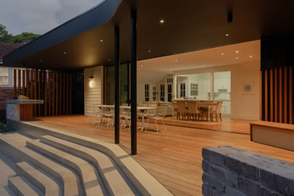 Open-plan living and dining area flowing onto hardwood deck through full-height glazing – Pymble renovation