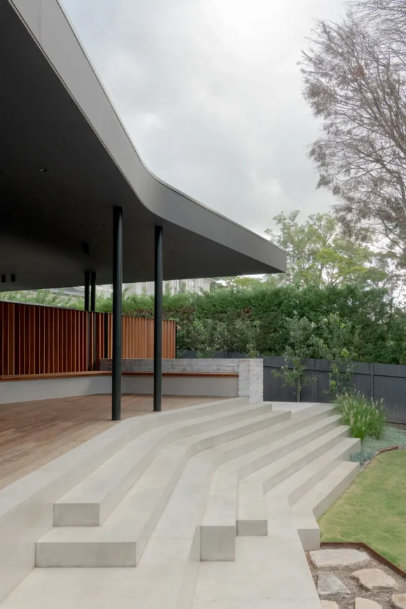 Curved cantilevered steel awning over rear deck and concrete amphitheatre steps – Pymble project