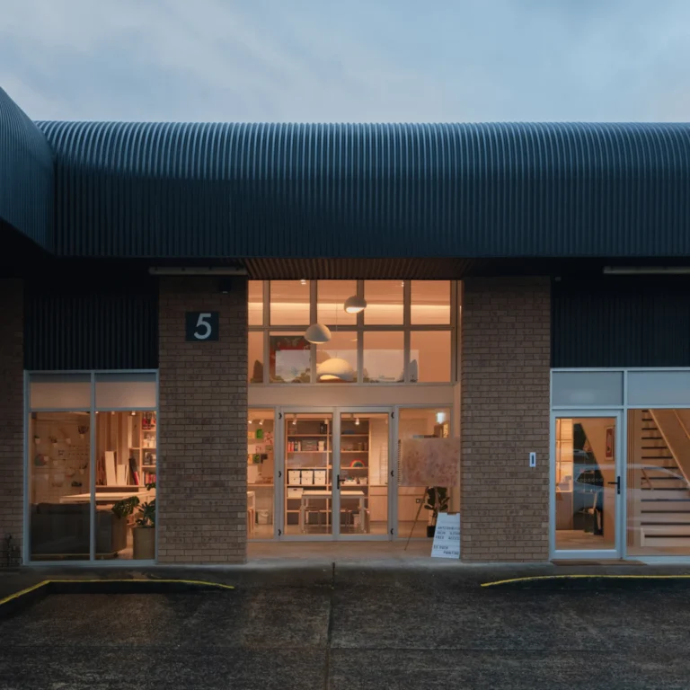 Kamispace creative hub in Erina at dusk, brick and corrugated warehouse exterior with warm-lit entry